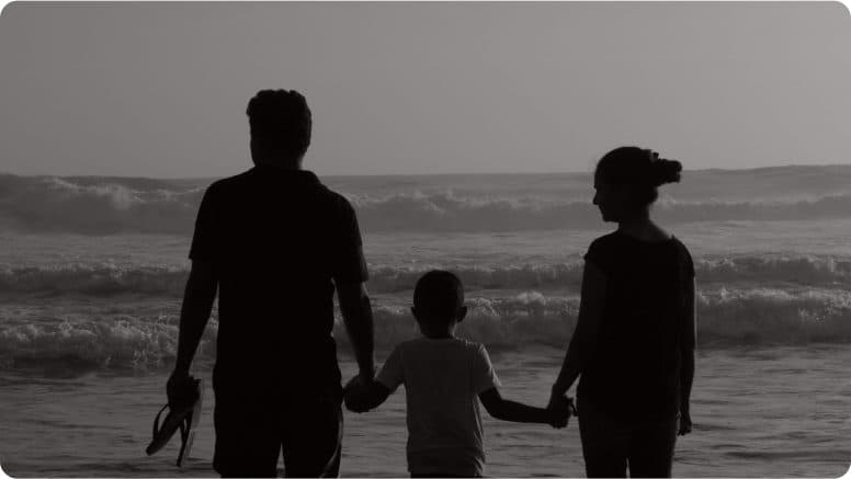 A family walking together along the shoreline at dusk