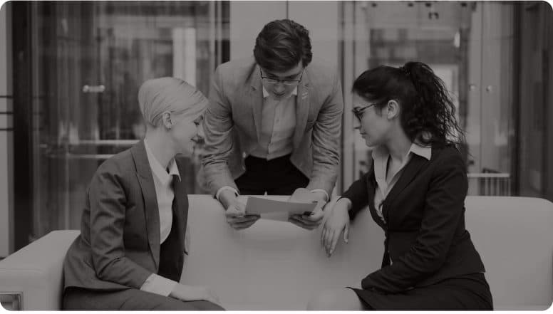 Three colleagues reviewing a document together in an office lobby