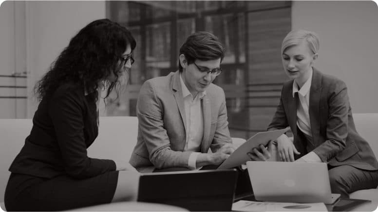 Three colleagues reviewing paperwork at a meeting table