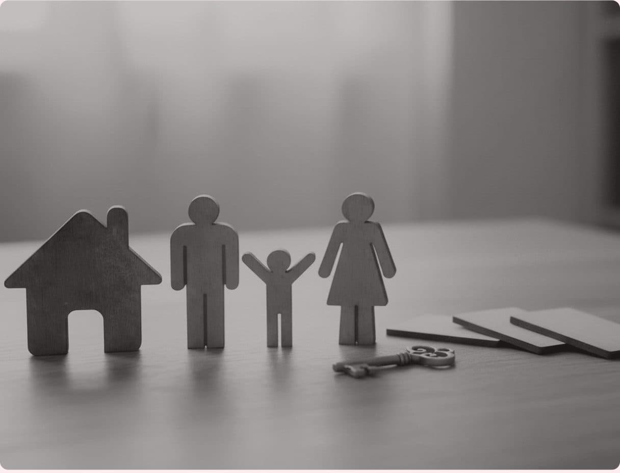 A wooden family figurine and house beside a set of keys